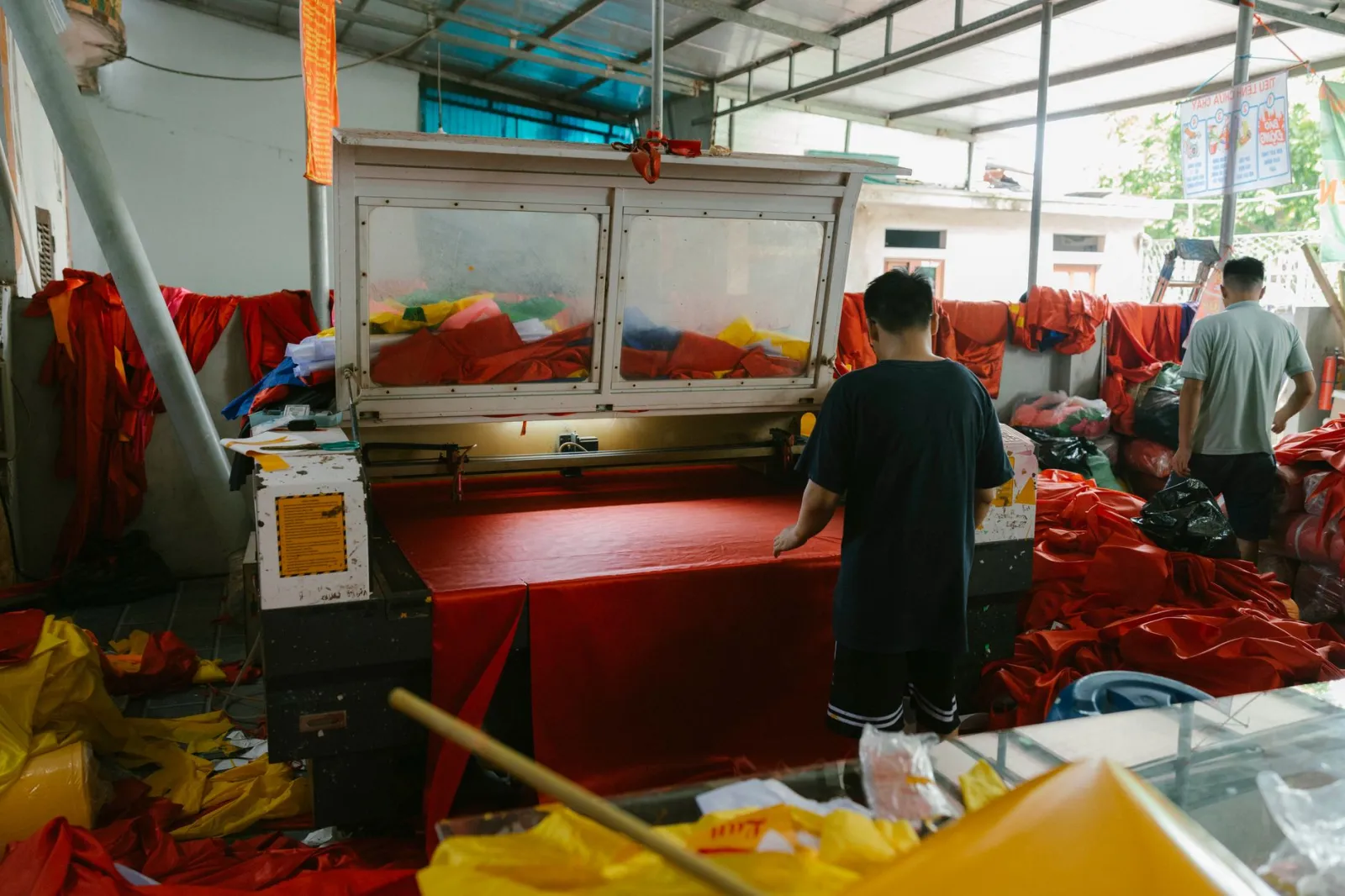 Workers operate machinery in a vibrant textile workshop with colorful fabrics.