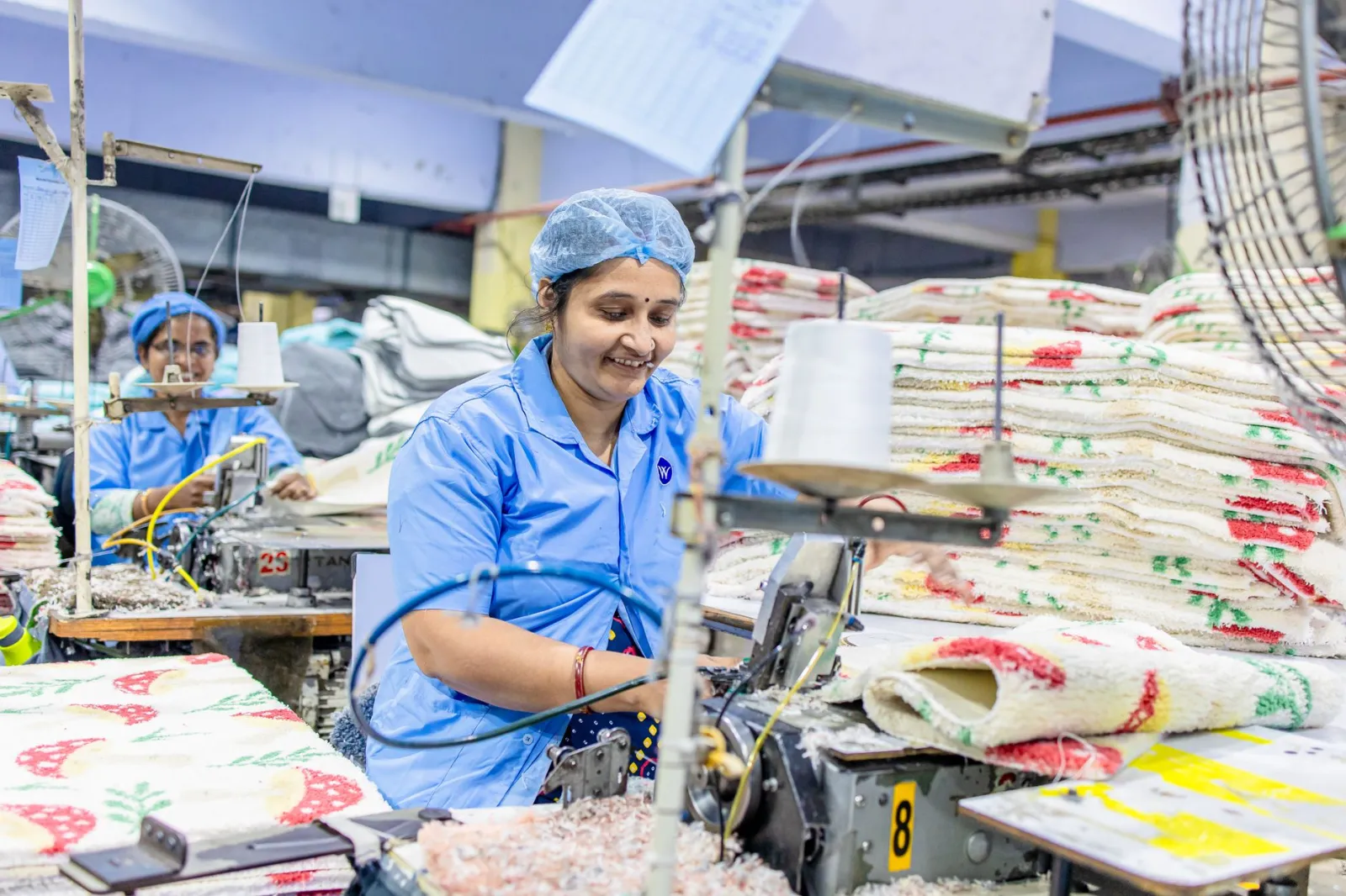 Women operate sewing machines in a vibrant textile factory, producing colorful fabrics.