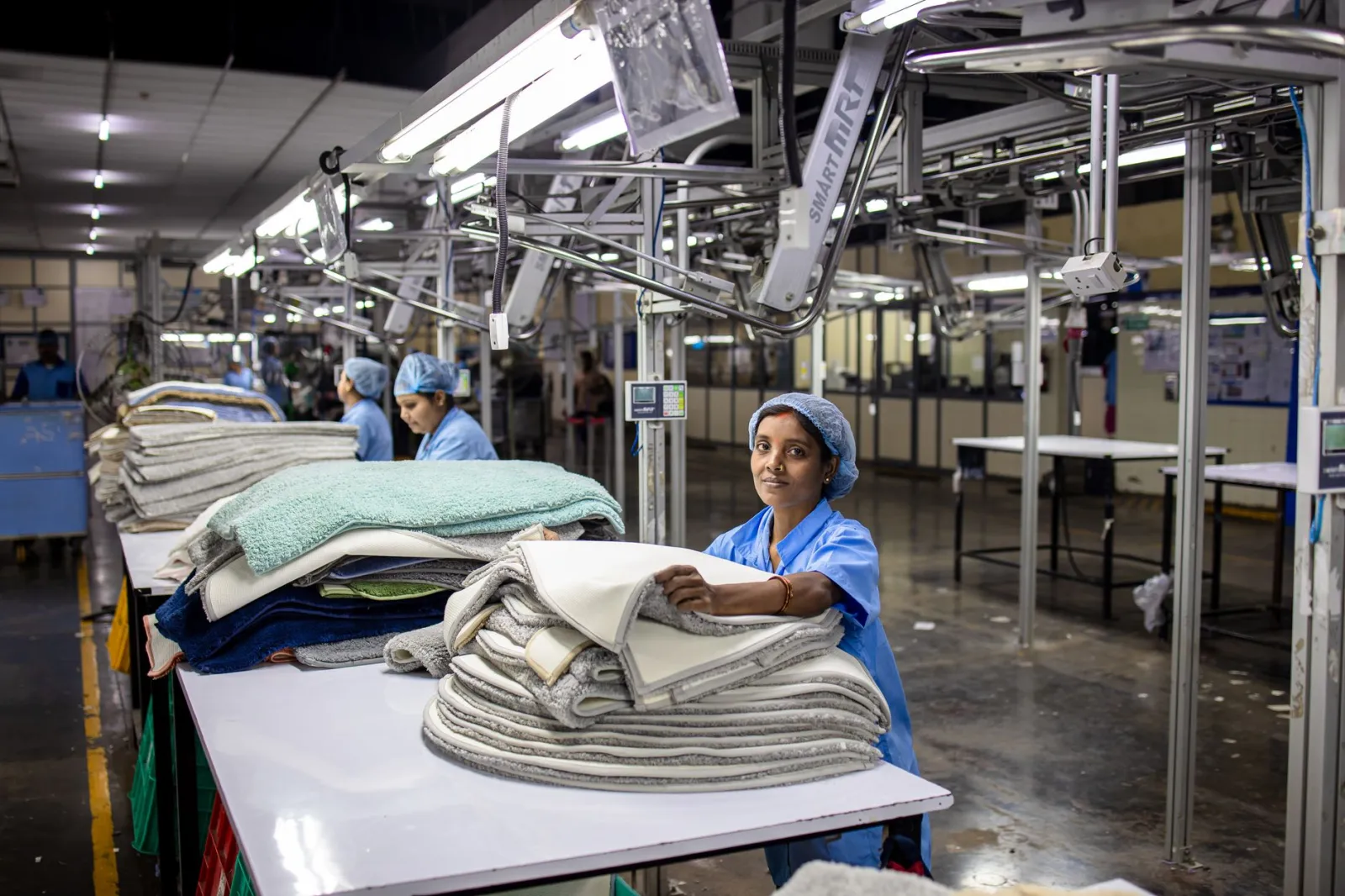 A female factory worker organizes textiles in an industrial setting, showcasing blue-collar work.