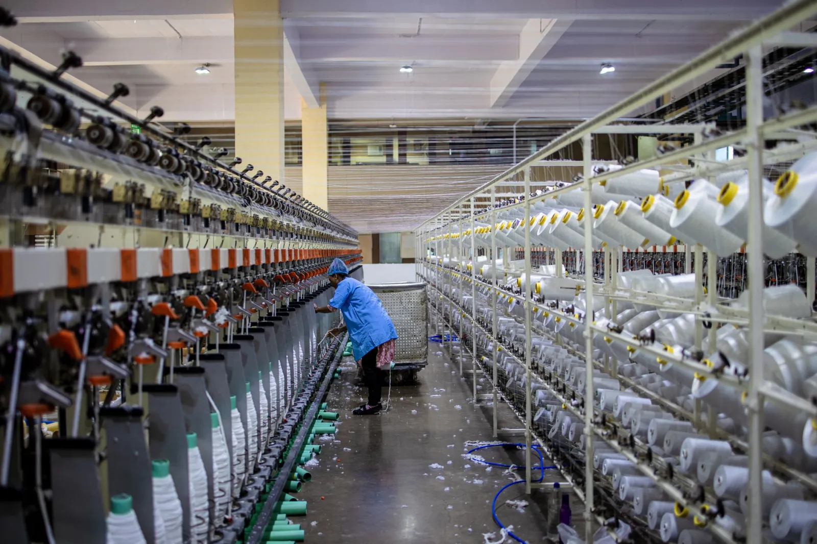 A textile worker handling machinery in a modern factory setting.