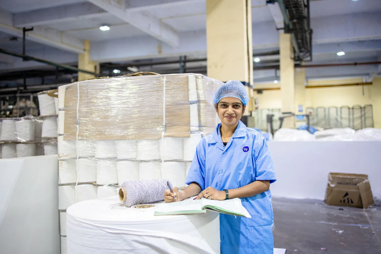 Female worker in textile factory checking yarn rolls, showcasing industry precision.