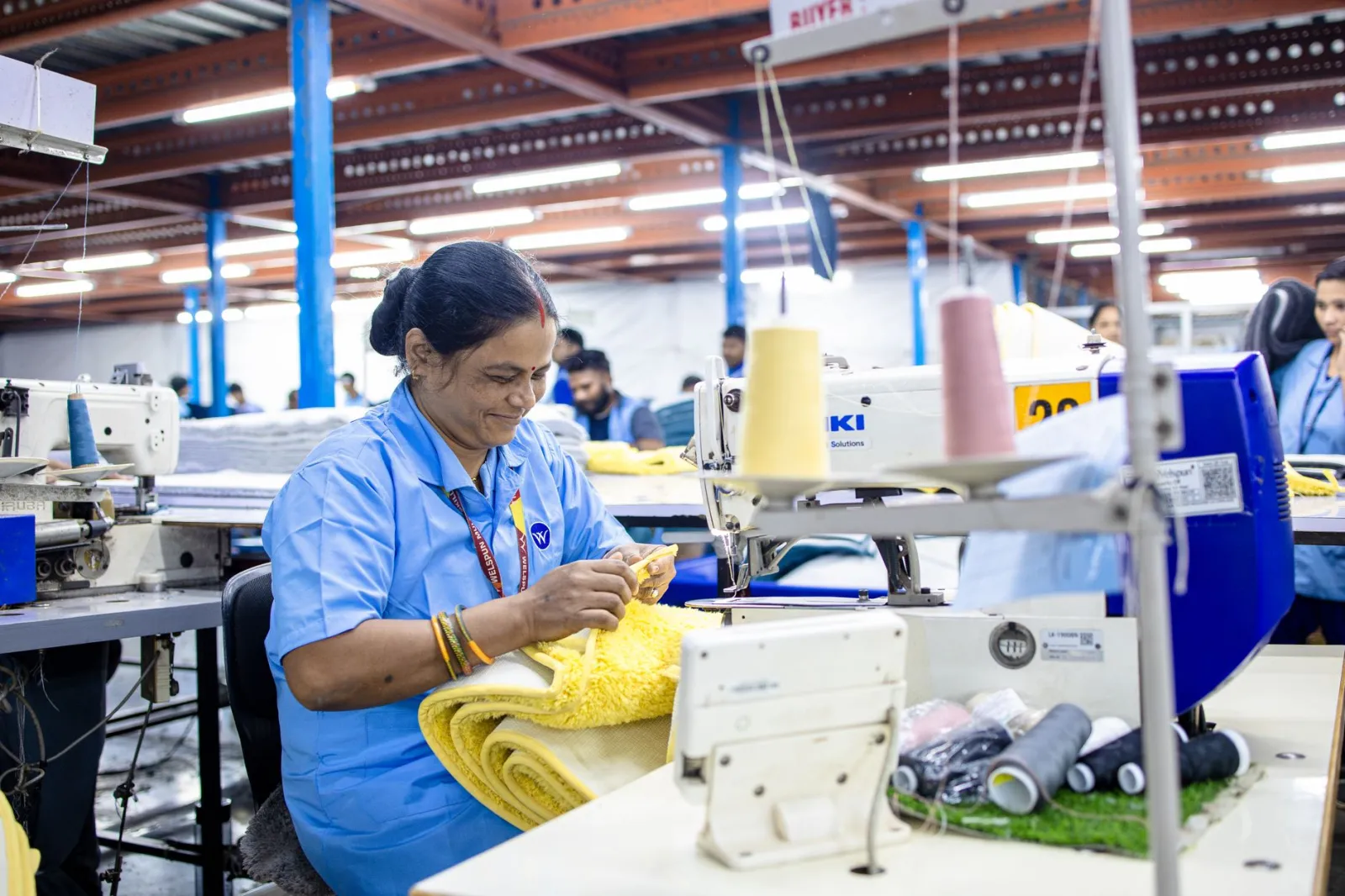 Indian woman working diligently in a textile factory sewing fabric.